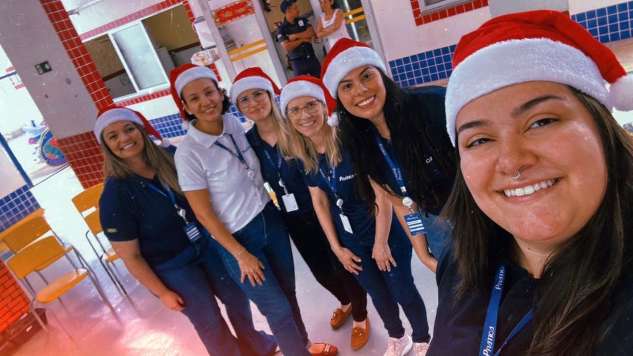 Um grupo de mulheres usando chapéus de Papai Noel estão posando para uma foto.