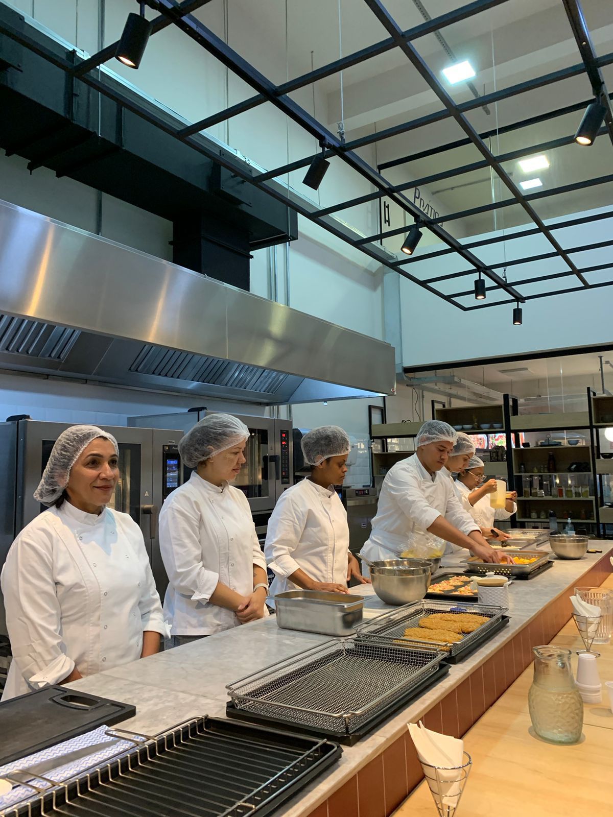 Um grupo de chefs está preparando comida em uma cozinha.