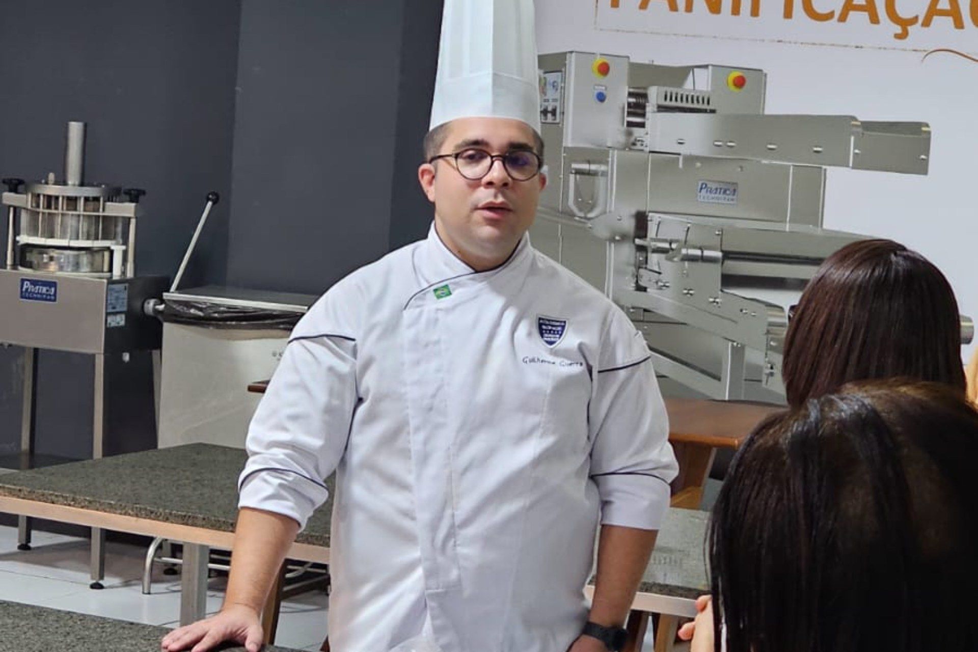 Um homem com chapéu de chef está conversando com um grupo de pessoas
