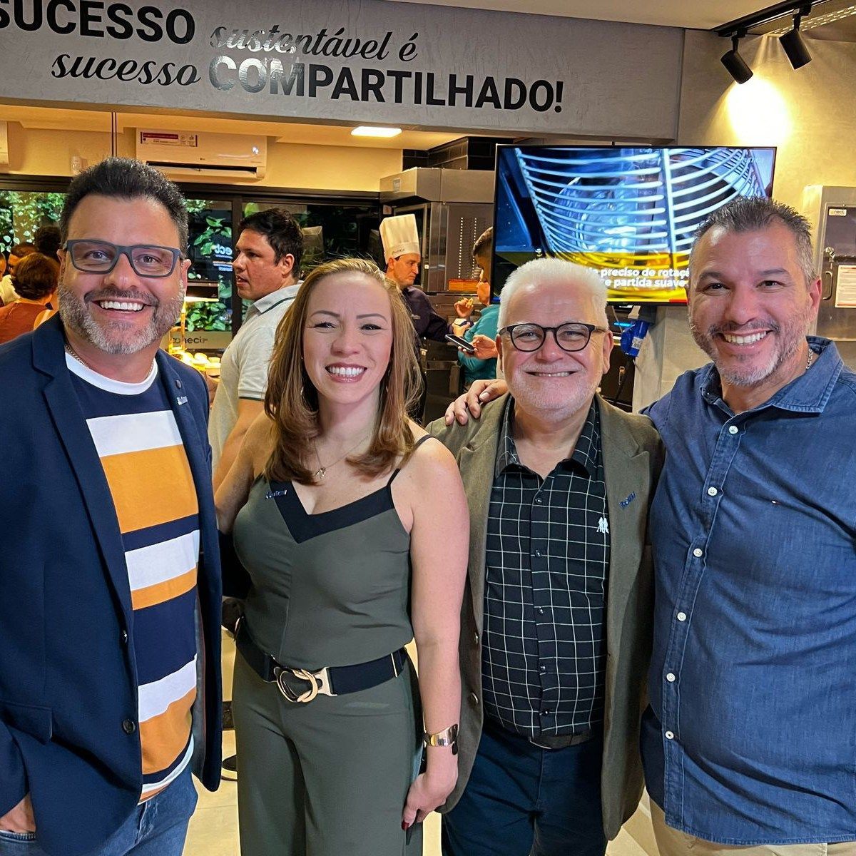 Um grupo de pessoas posando para uma foto em frente a uma placa que diz sucesso