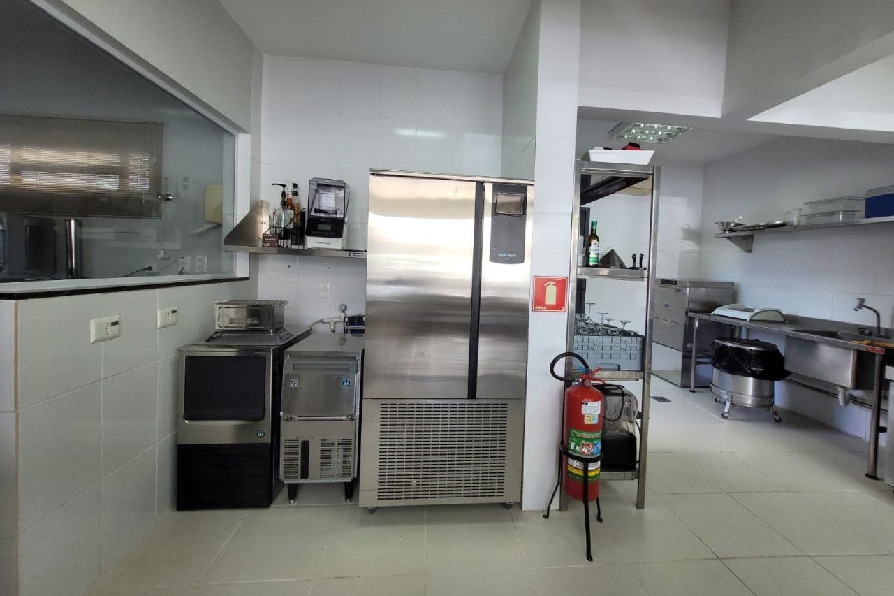 Uma cozinha com uma geladeira de aço inoxidável e um extintor de incêndio.
