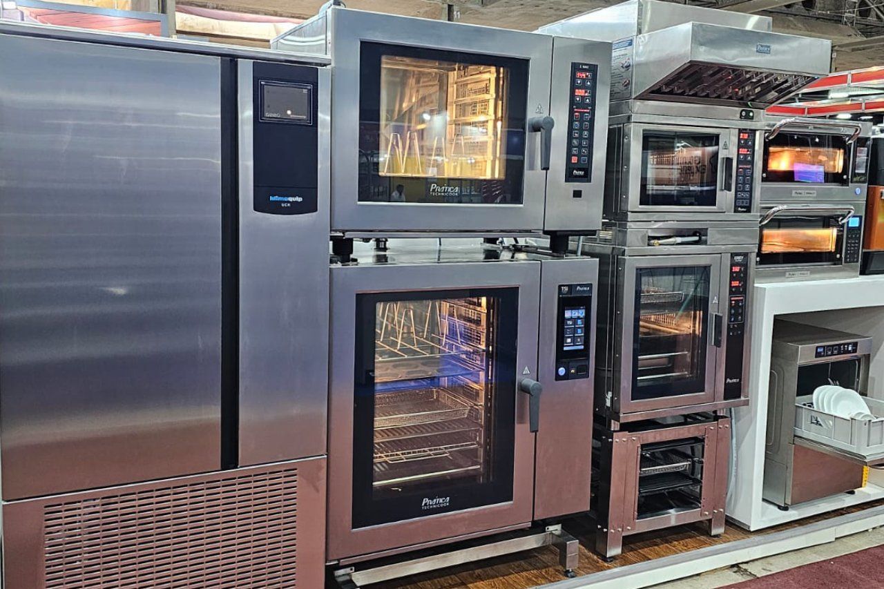 Uma fileira de fornos de aço inoxidável estão dispostos um ao lado do outro em uma cozinha.