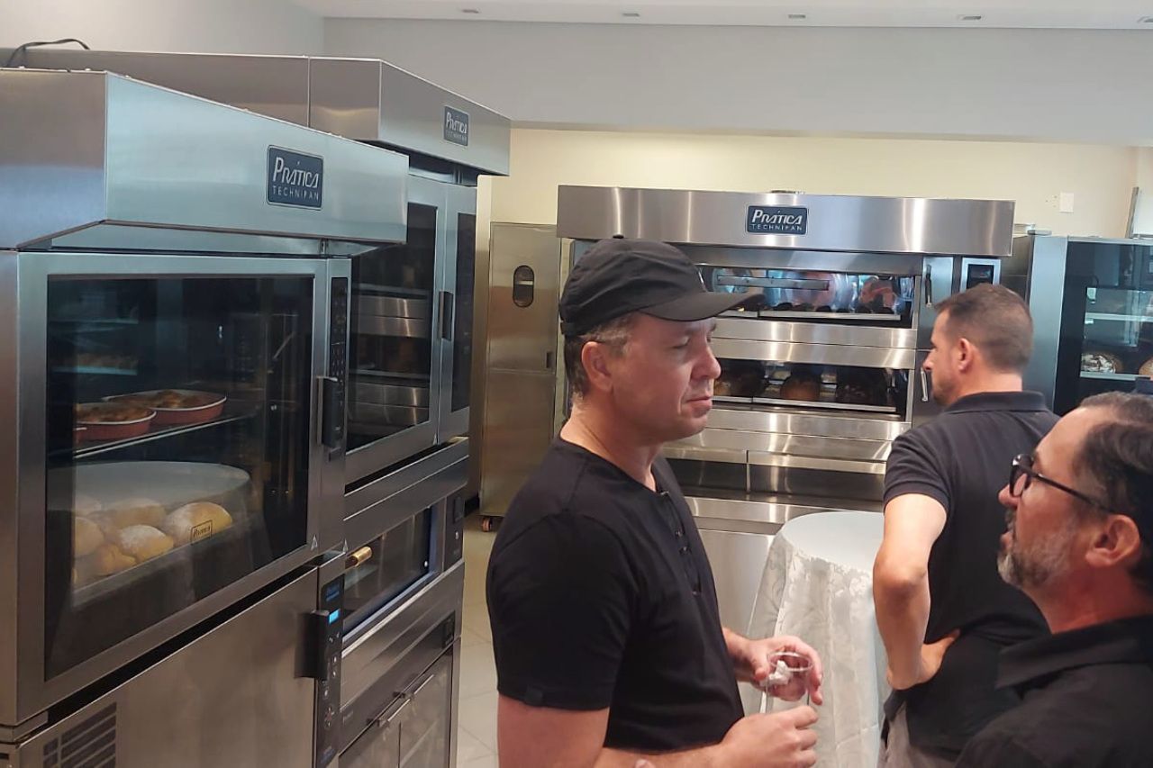 Um homem com boné de beisebol está conversando com outro homem na cozinha