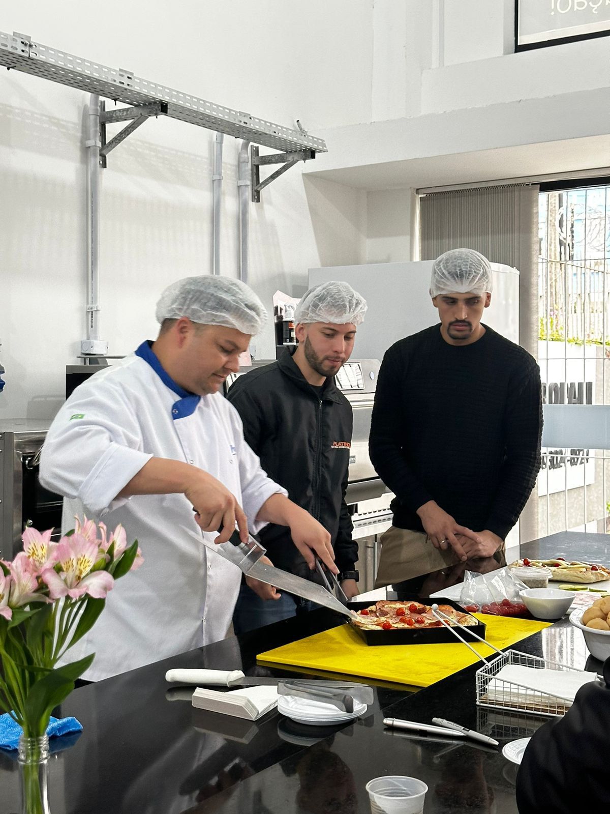 Um grupo de homens está em volta de uma mesa na cozinha preparando comida.