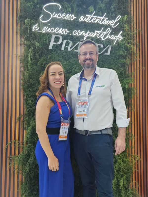 Um homem e uma mulher estão posando para uma foto em frente a uma placa que diz sucesso