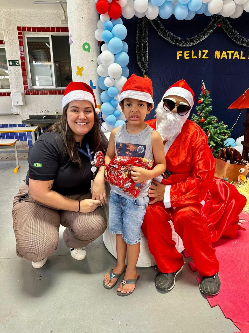 Uma mulher e uma criança estão posando para uma foto com o papai noel.