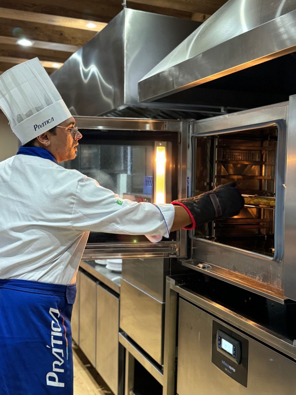 Um chef está tirando comida do forno em uma cozinha.
