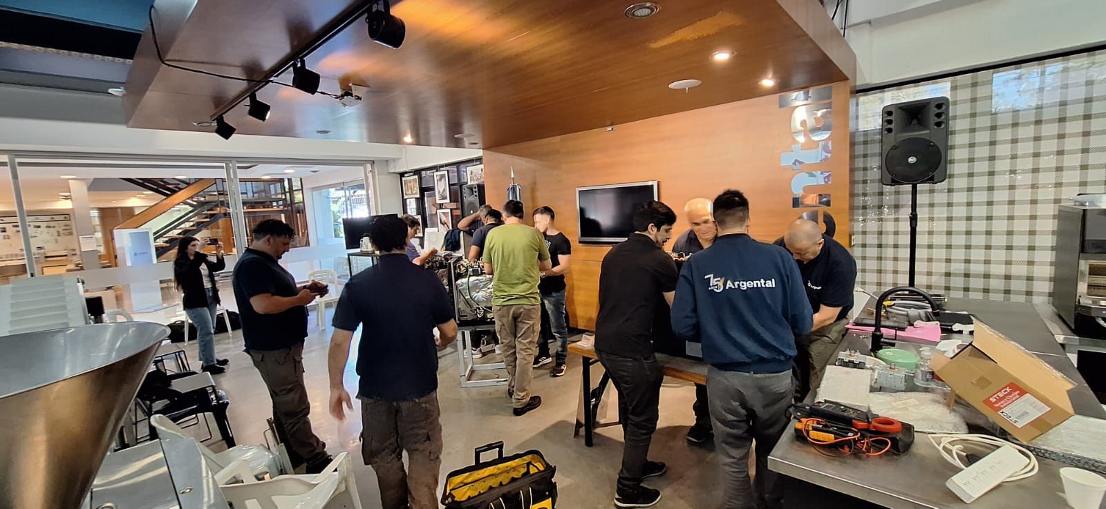 Pessoas dentro de uma cafeteria ou café, montando equipamentos e uma TV.