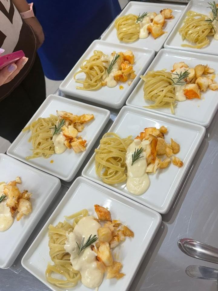 Pratos de massa com lagosta e molho cremoso, guarnecido com alecrim, prontos para servir.