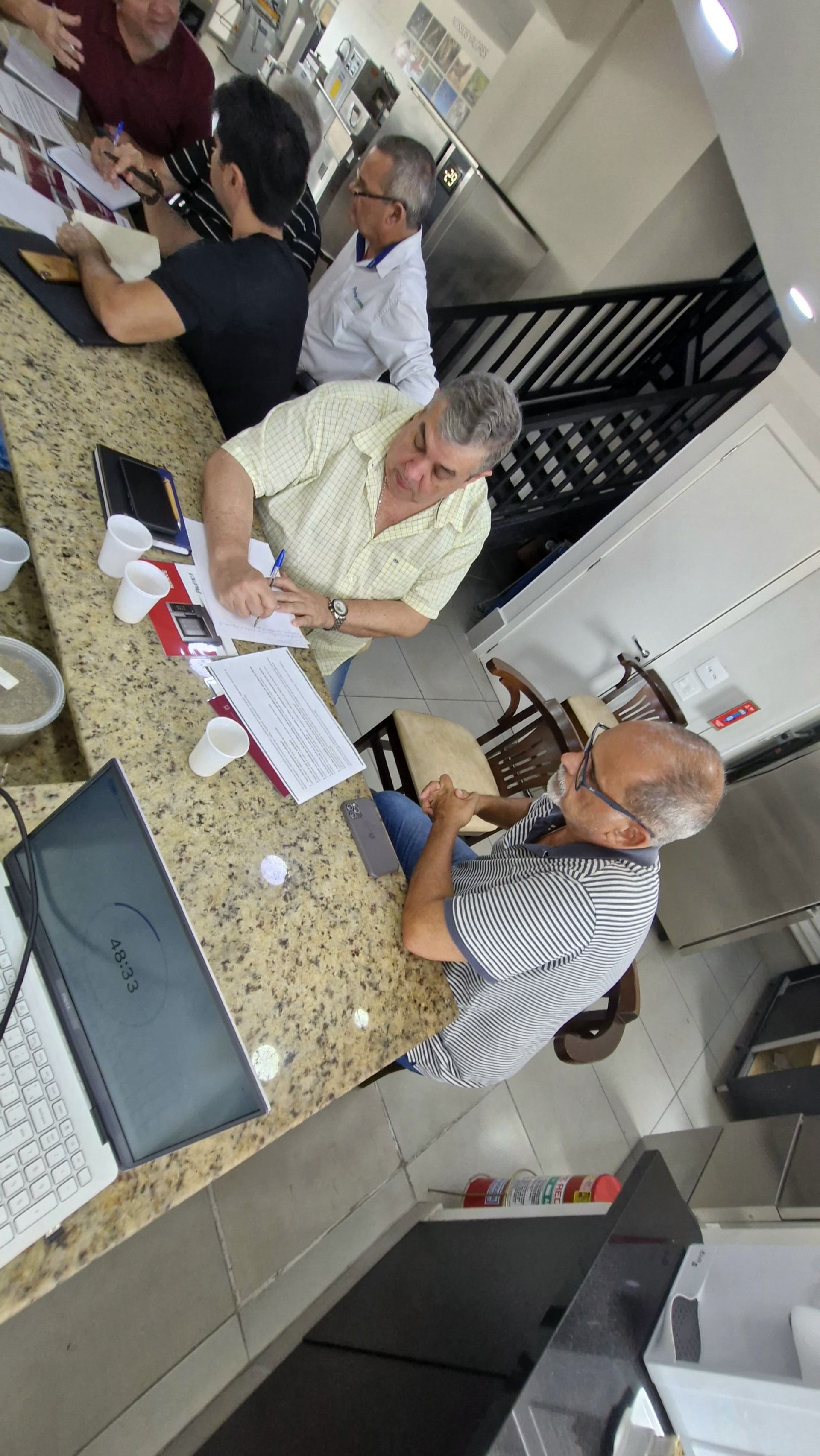 Um grupo de homens está sentado à mesa na cozinha.