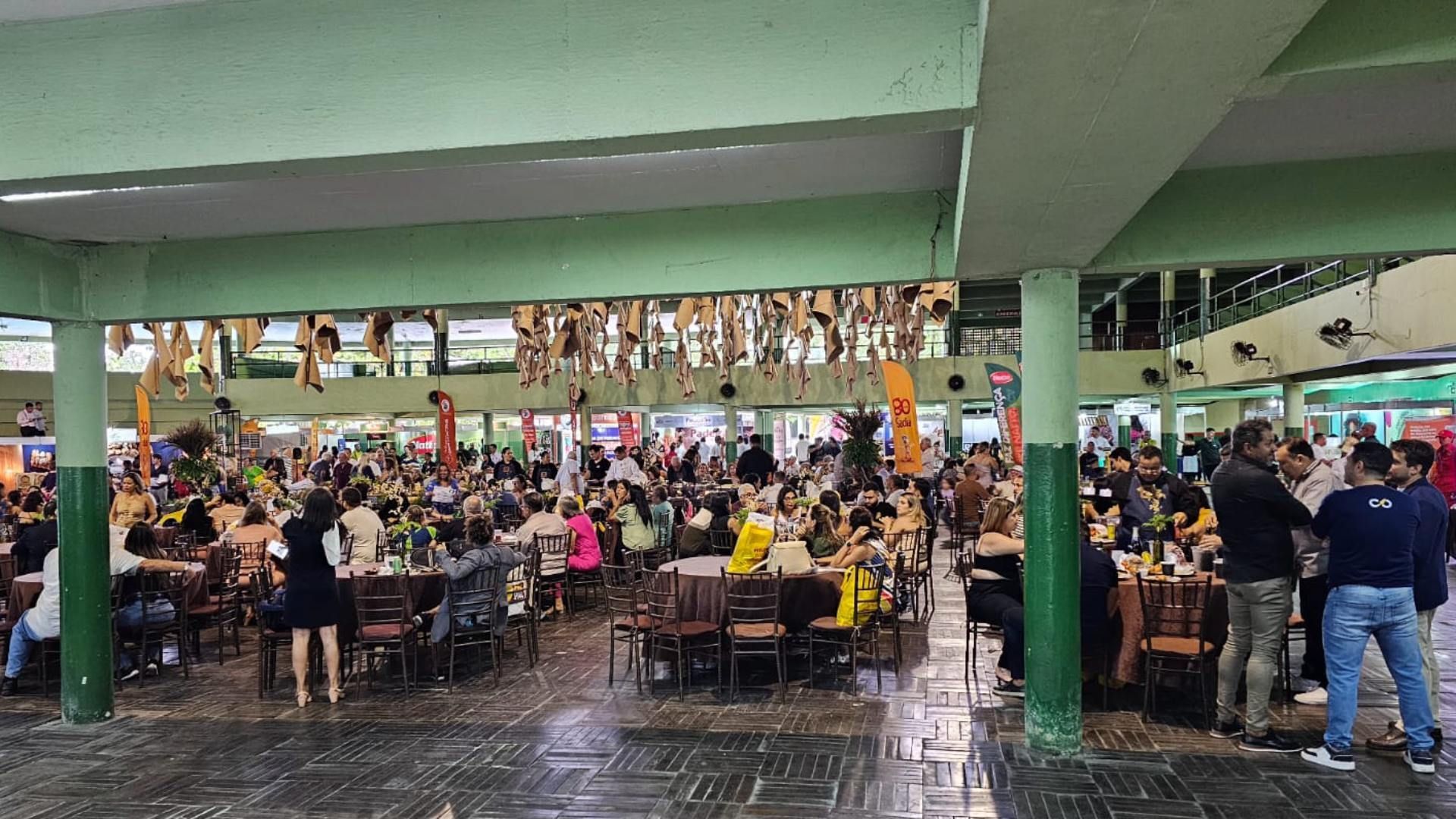 Um grande grupo de pessoas está sentado em mesas em um restaurante.