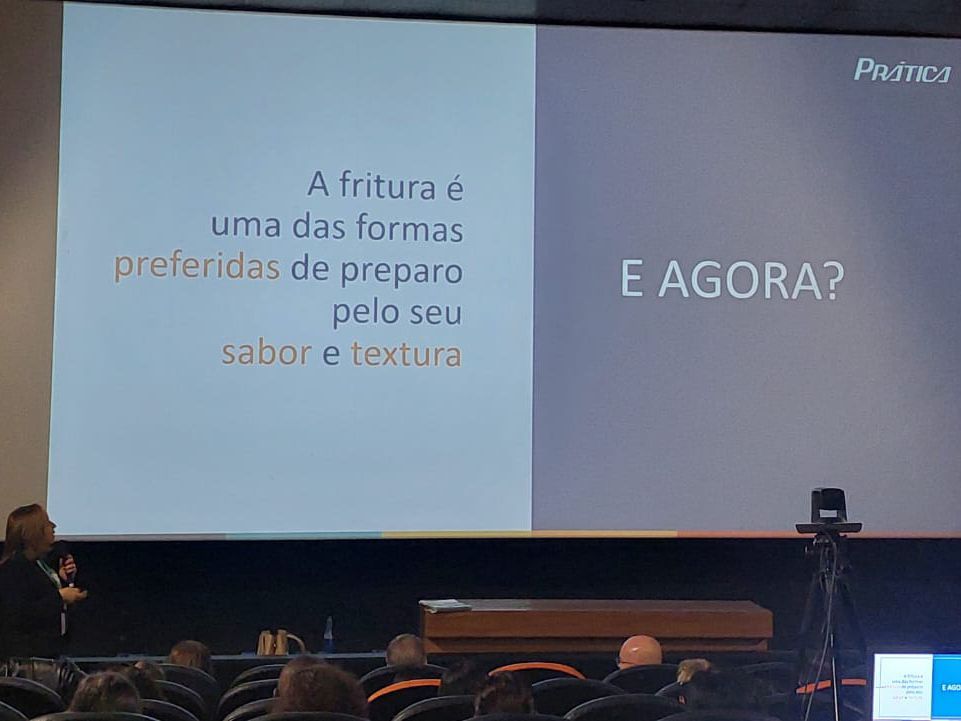 Um grupo de pessoas está sentado em frente a uma tela grande que diz e agora
