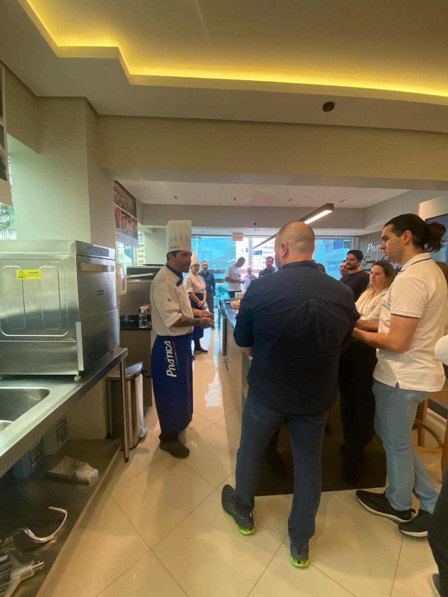 Um grupo de pessoas está em uma cozinha conversando com um chef.