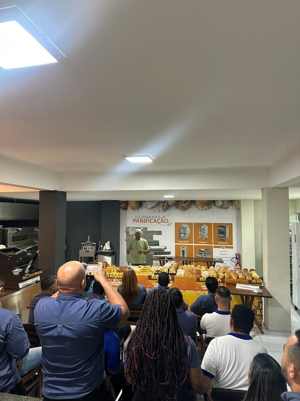 Um grupo de pessoas está sentado em uma sala assistindo a uma apresentação