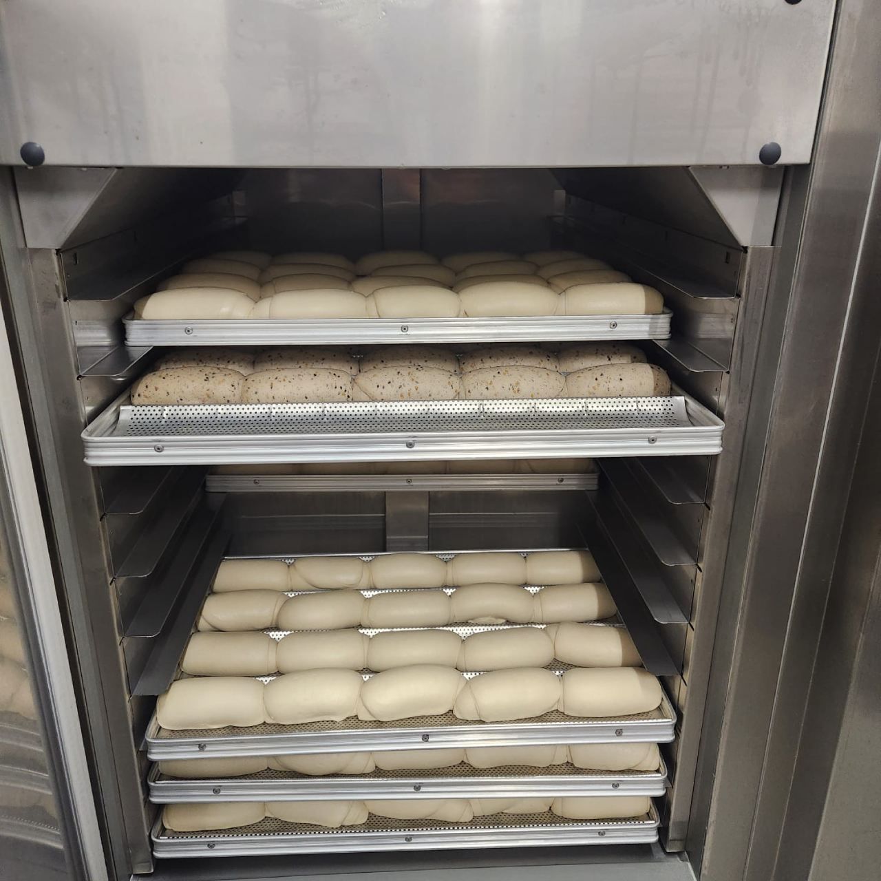Um forno de aço inoxidável cheio de bandejas de pão