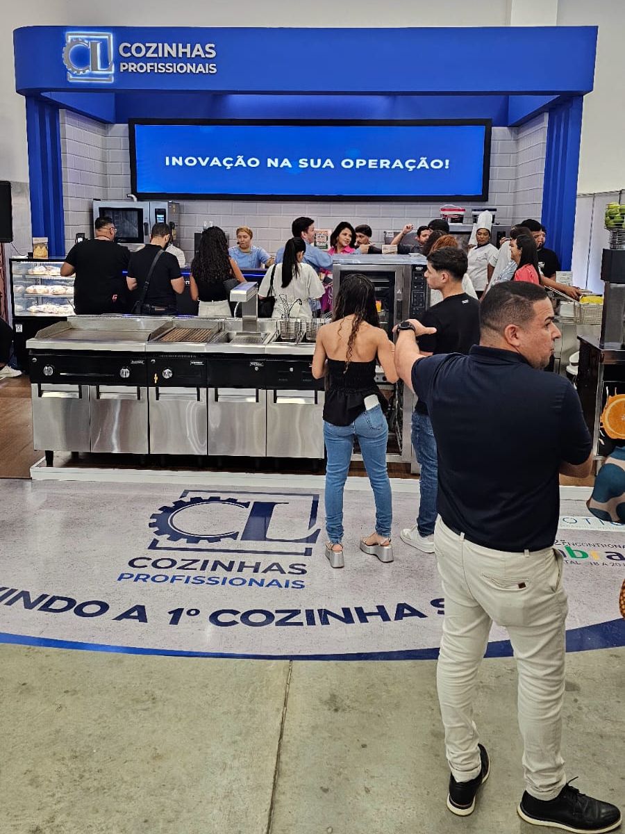 Um grupo de pessoas está em frente a uma vitrine de cozinhas