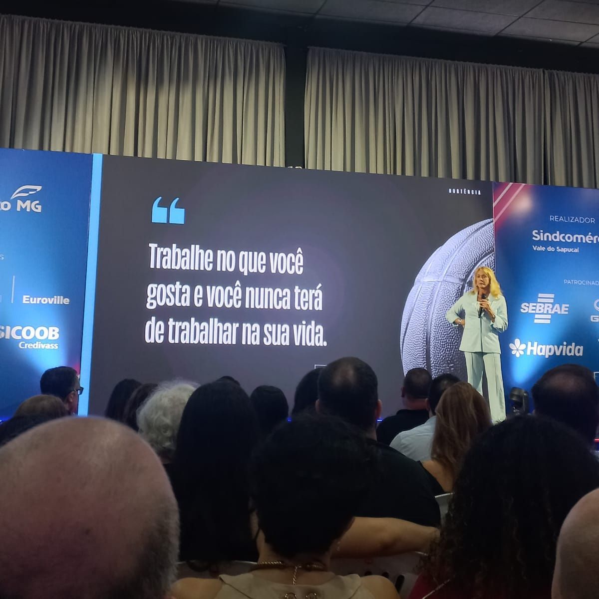 A woman stands in front of a screen that says trabalha no que você