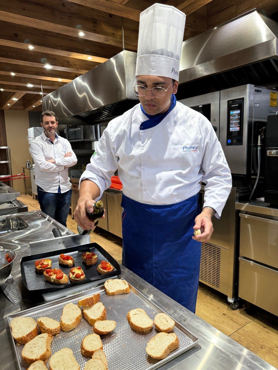Um homem com chapéu de chef está preparando comida na cozinha.