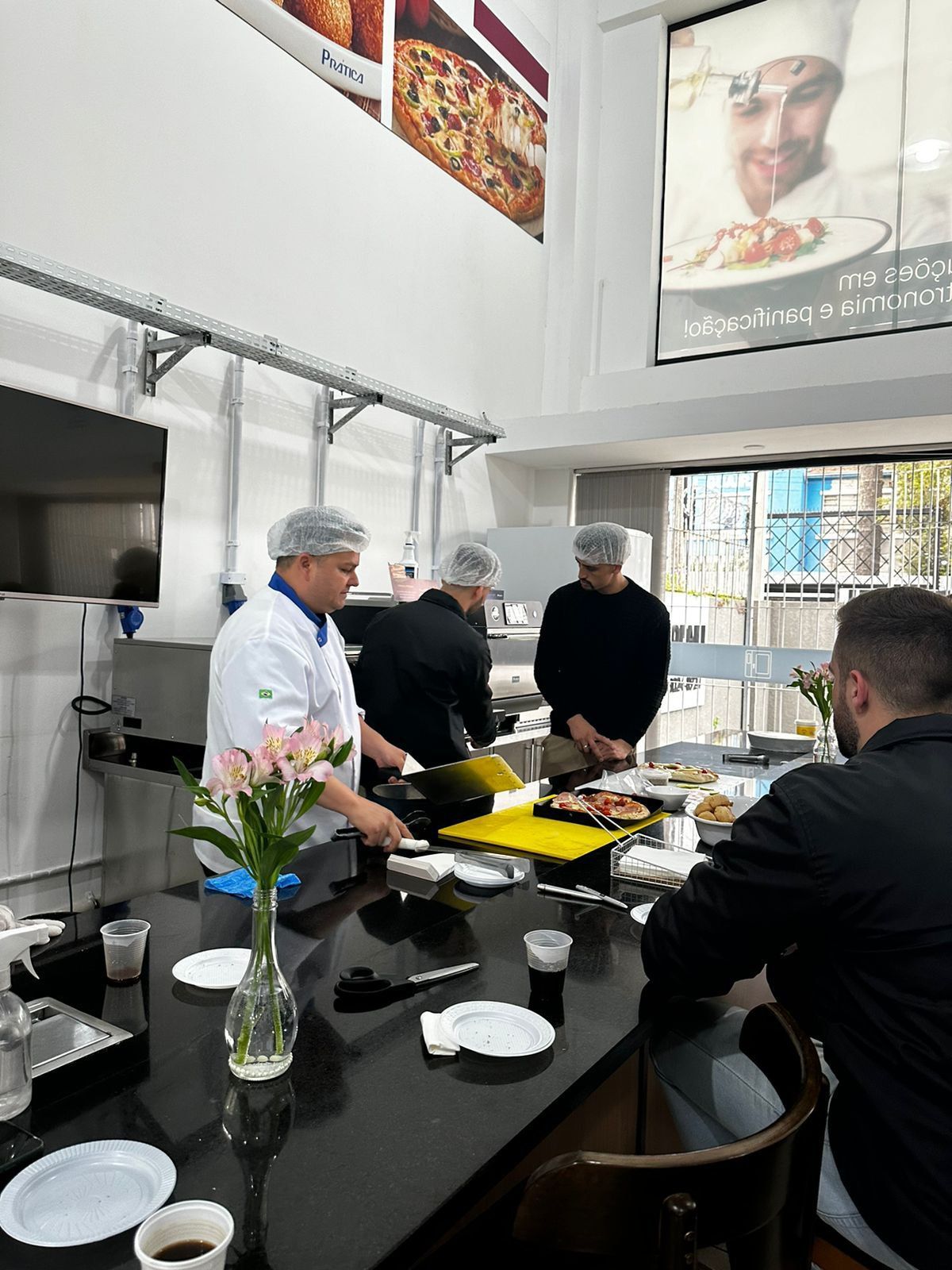 Um grupo de homens está sentado à mesa em uma cozinha preparando comida.