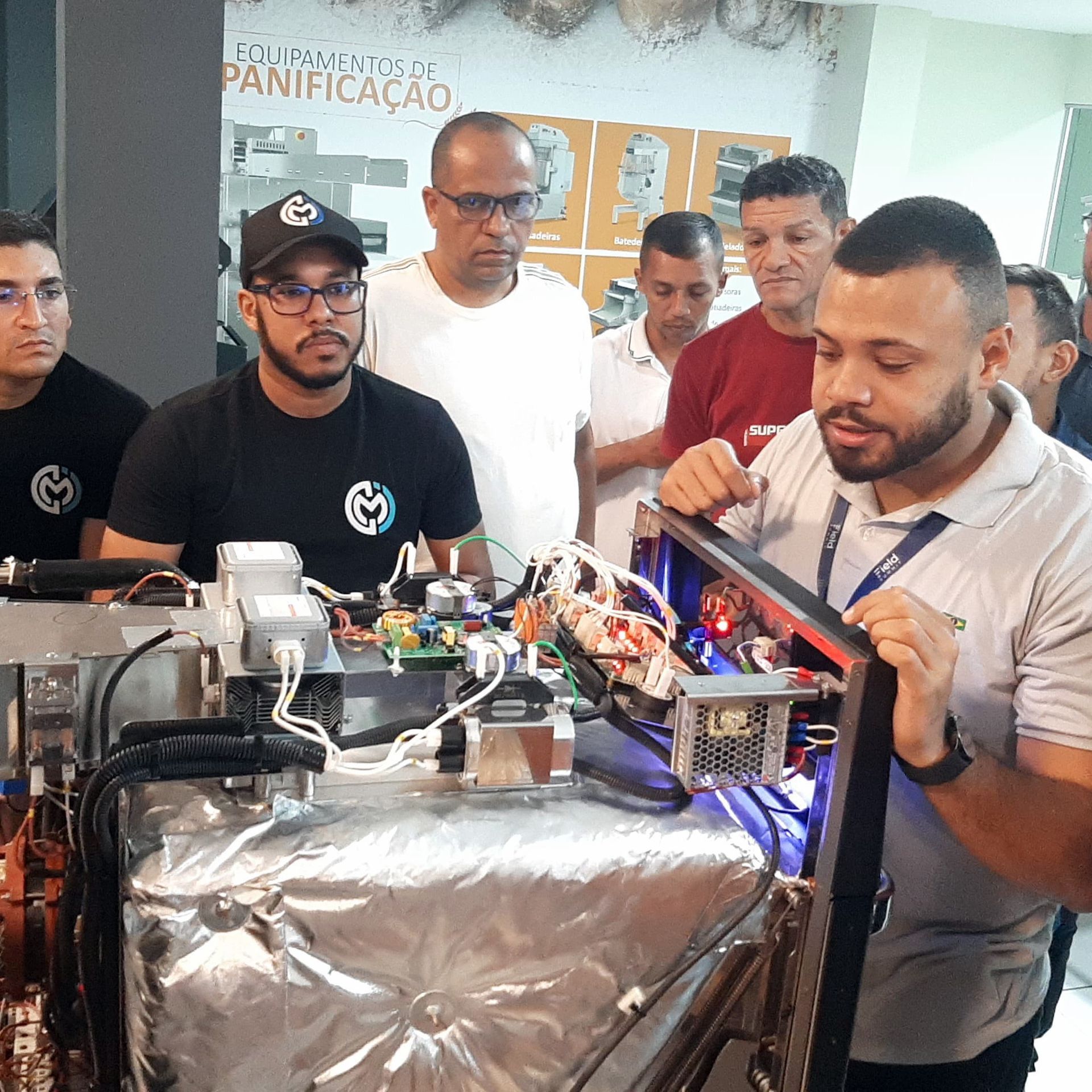 Um grupo de homens está em volta de uma máquina que diz panificação