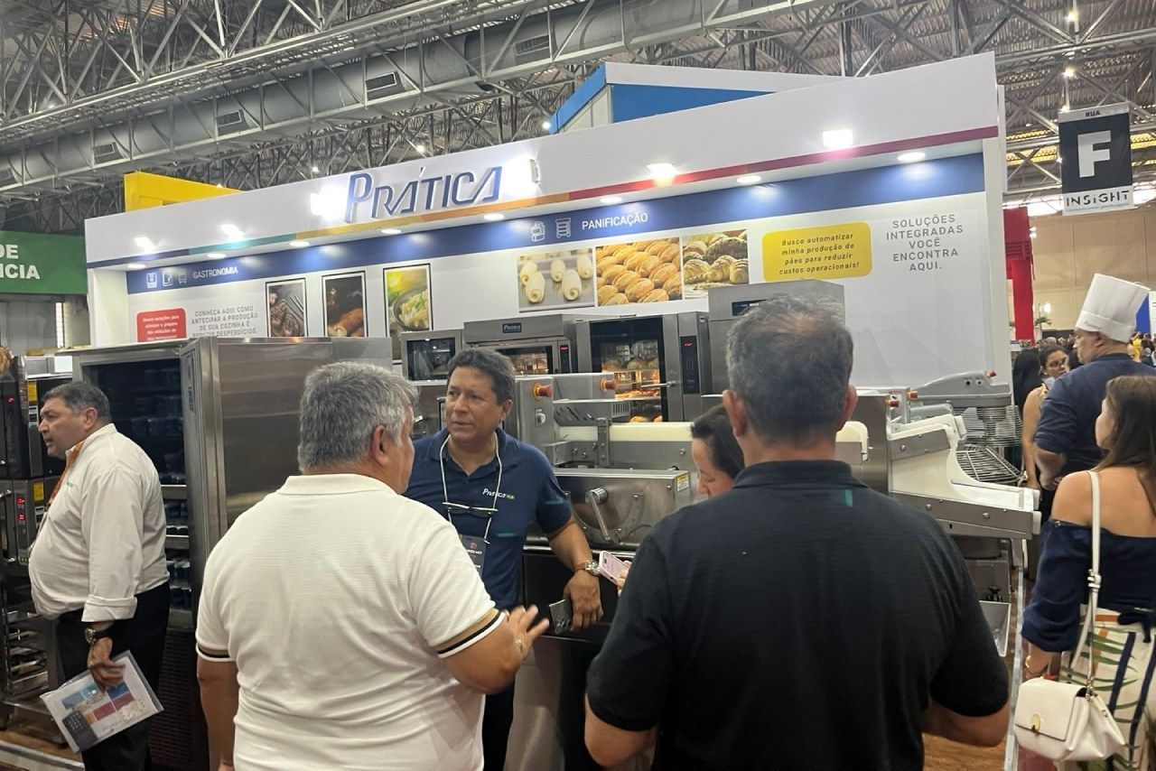 Um grupo de pessoas está em frente a um estande em uma feira de alimentos.