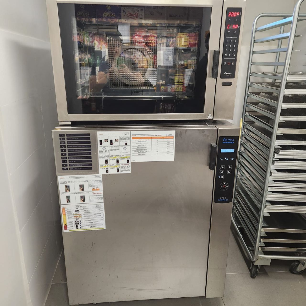 Um forno de aço inoxidável está ao lado de uma prateleira de bandejas.
