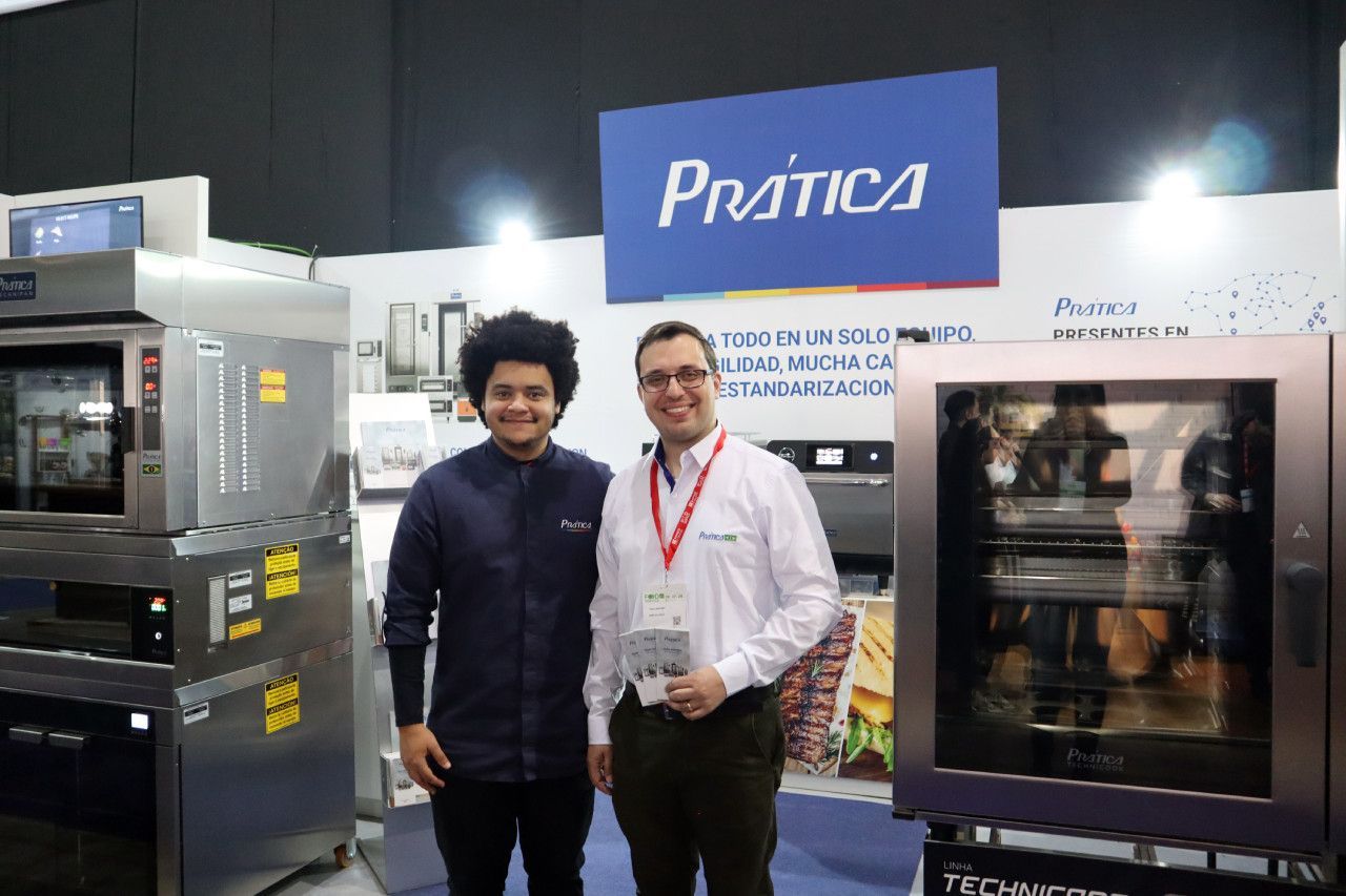 Dois homens estão parados um ao lado do outro em frente a uma placa de prática.