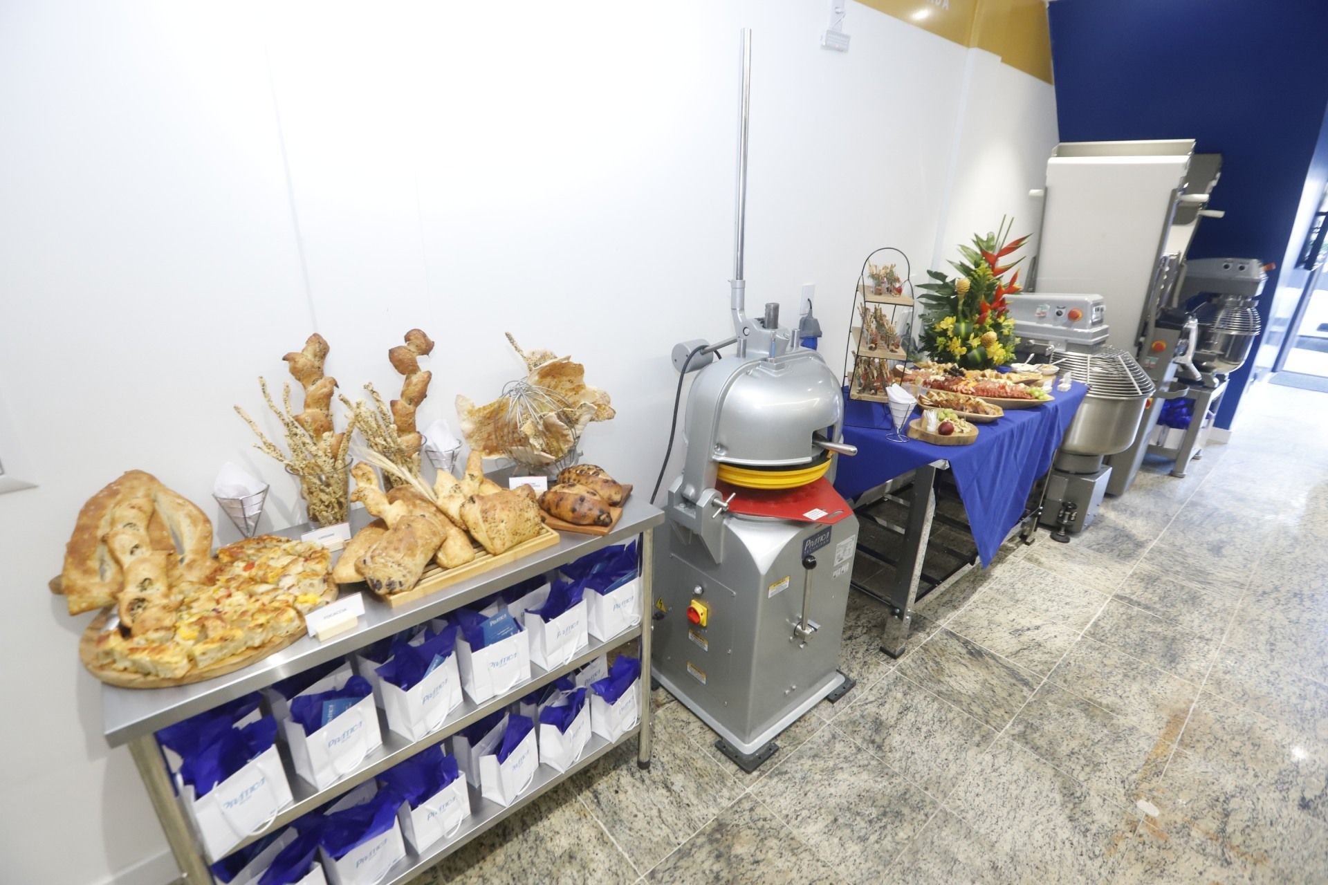 Exposição de pães com equipamentos para panificação em um ambiente de padaria moderno e iluminado.