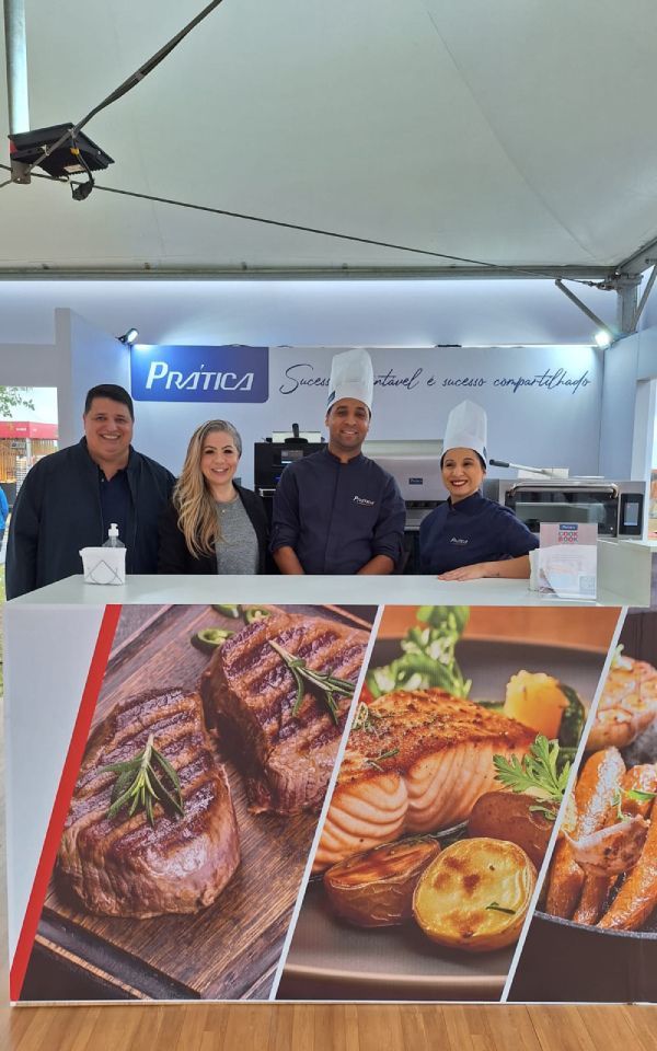 Um grupo de pessoas em pé atrás de um balcão com uma foto de comida nele.