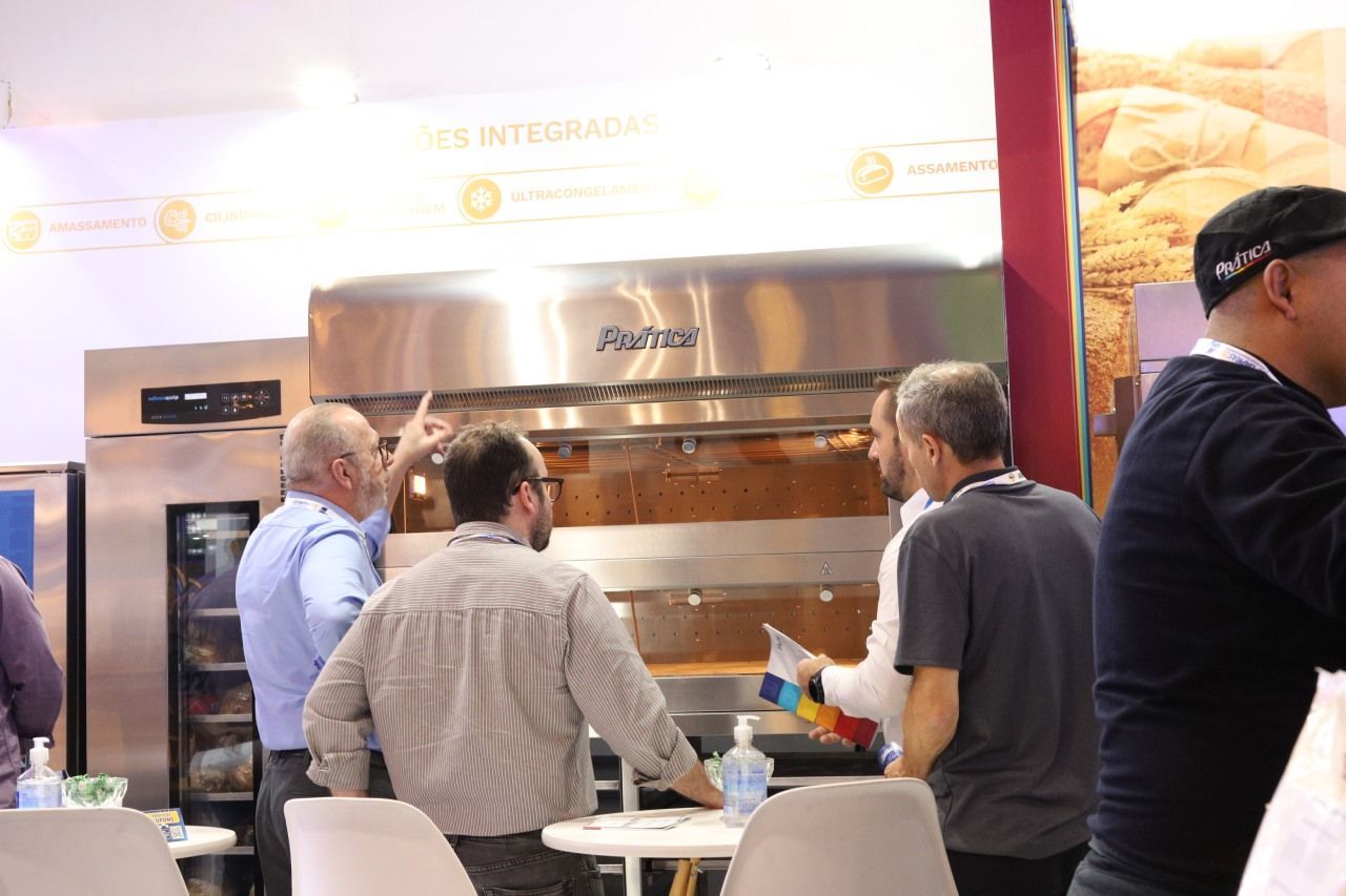 Um grupo de pessoas está em volta de um forno de aço inoxidável.
