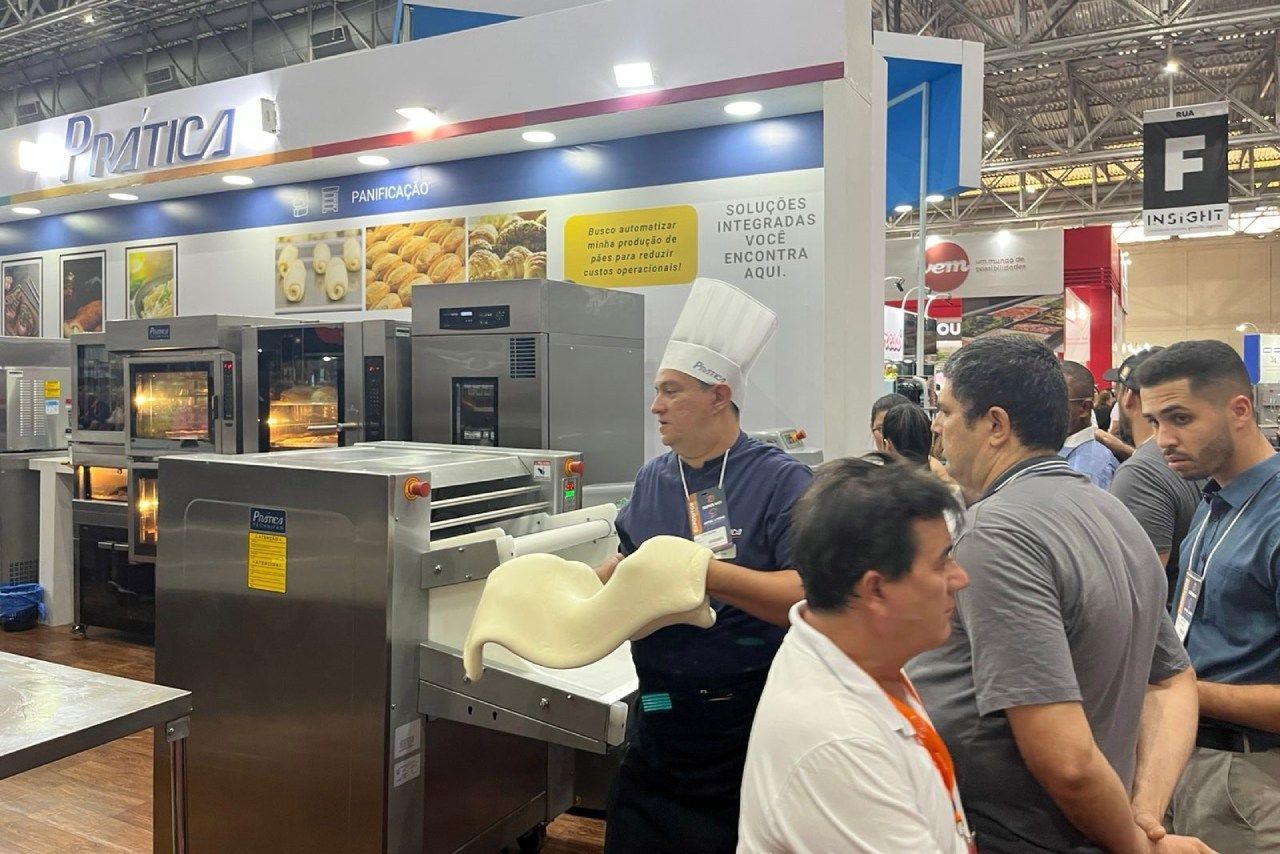 Um grupo de homens está em volta de uma máquina em uma feira de alimentos.
