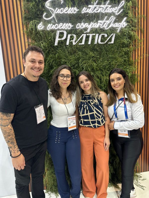 Um grupo de pessoas está posando para uma foto em frente a uma placa.