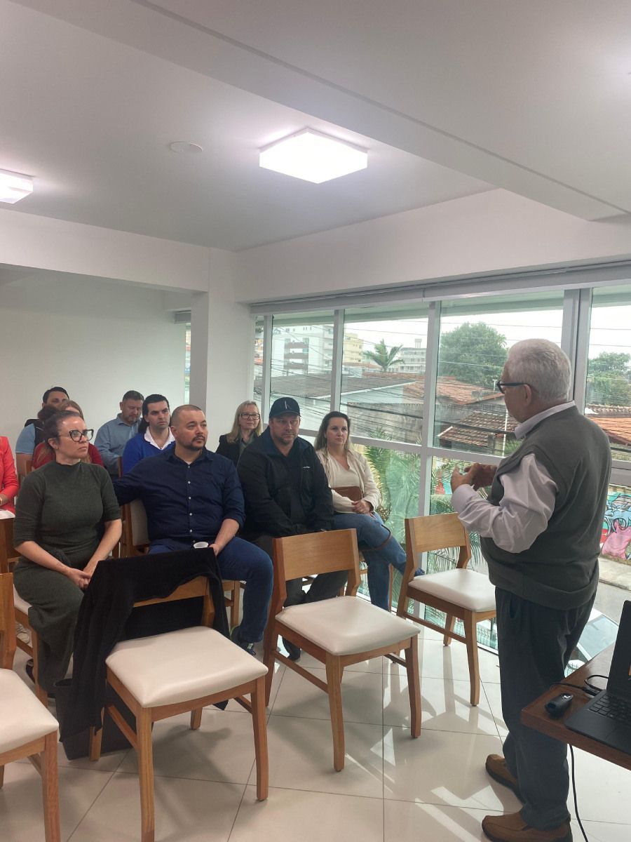 Um homem está fazendo uma apresentação para um grupo de pessoas sentadas em cadeiras.
