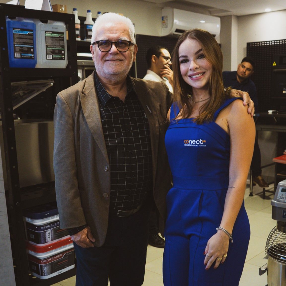 Um homem e uma mulher estão posando para uma foto em uma cozinha