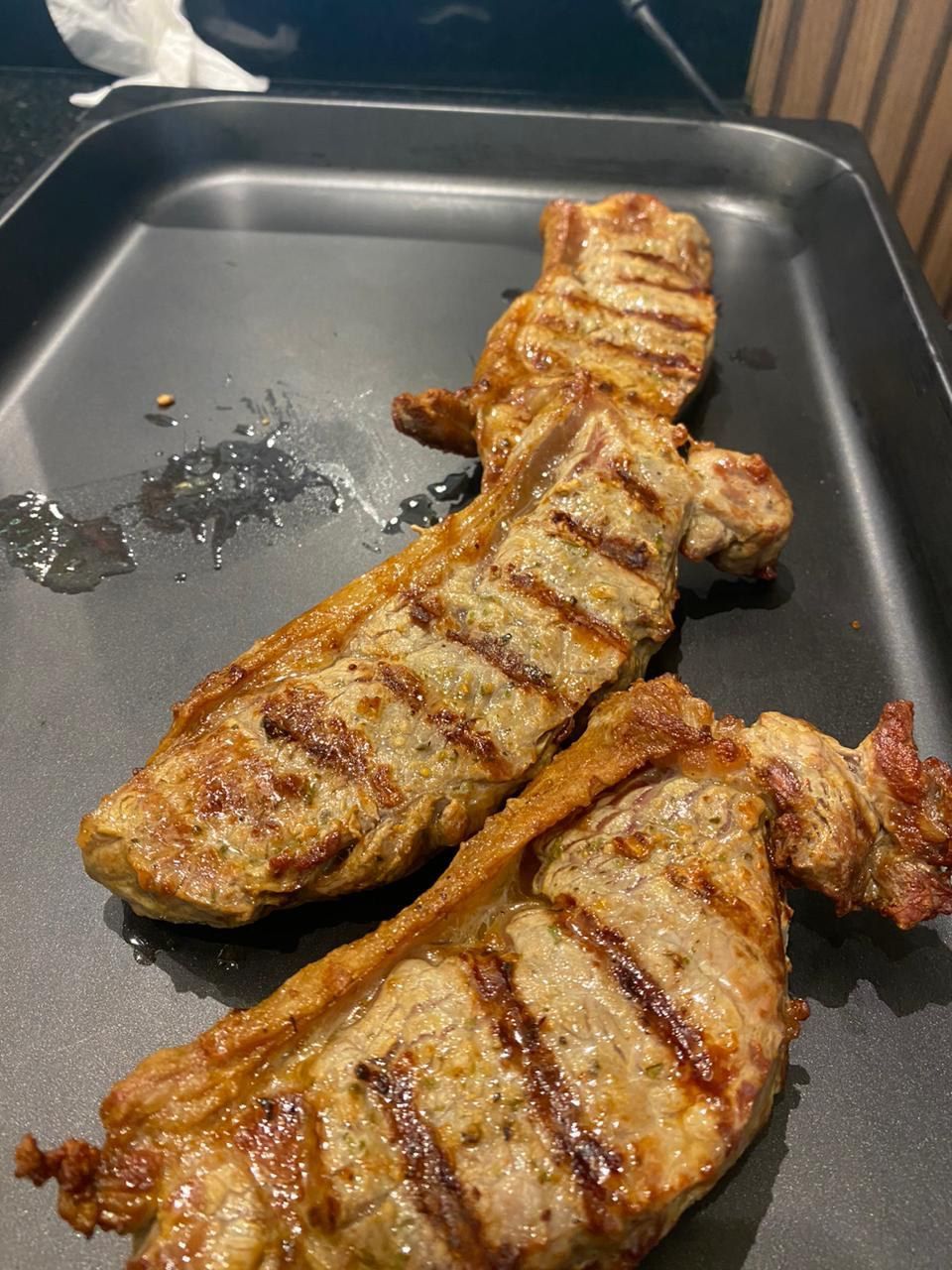 Duas costeletas de porco grelhadas estão em uma frigideira preta