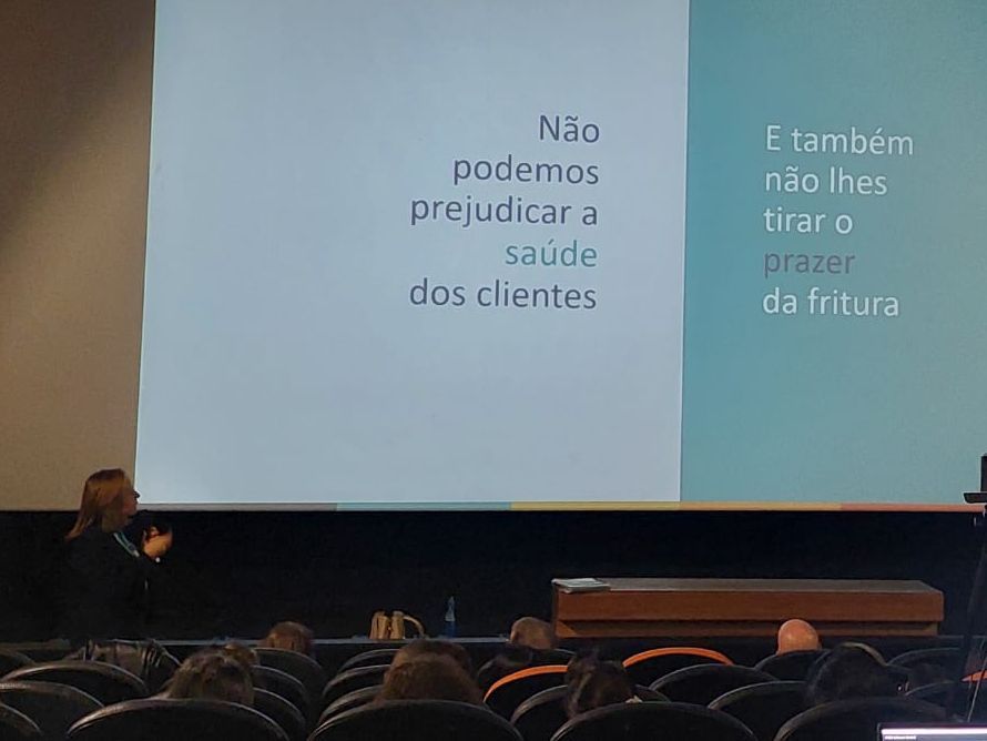 Uma mulher está fazendo uma apresentação para um grupo de pessoas em um auditório.