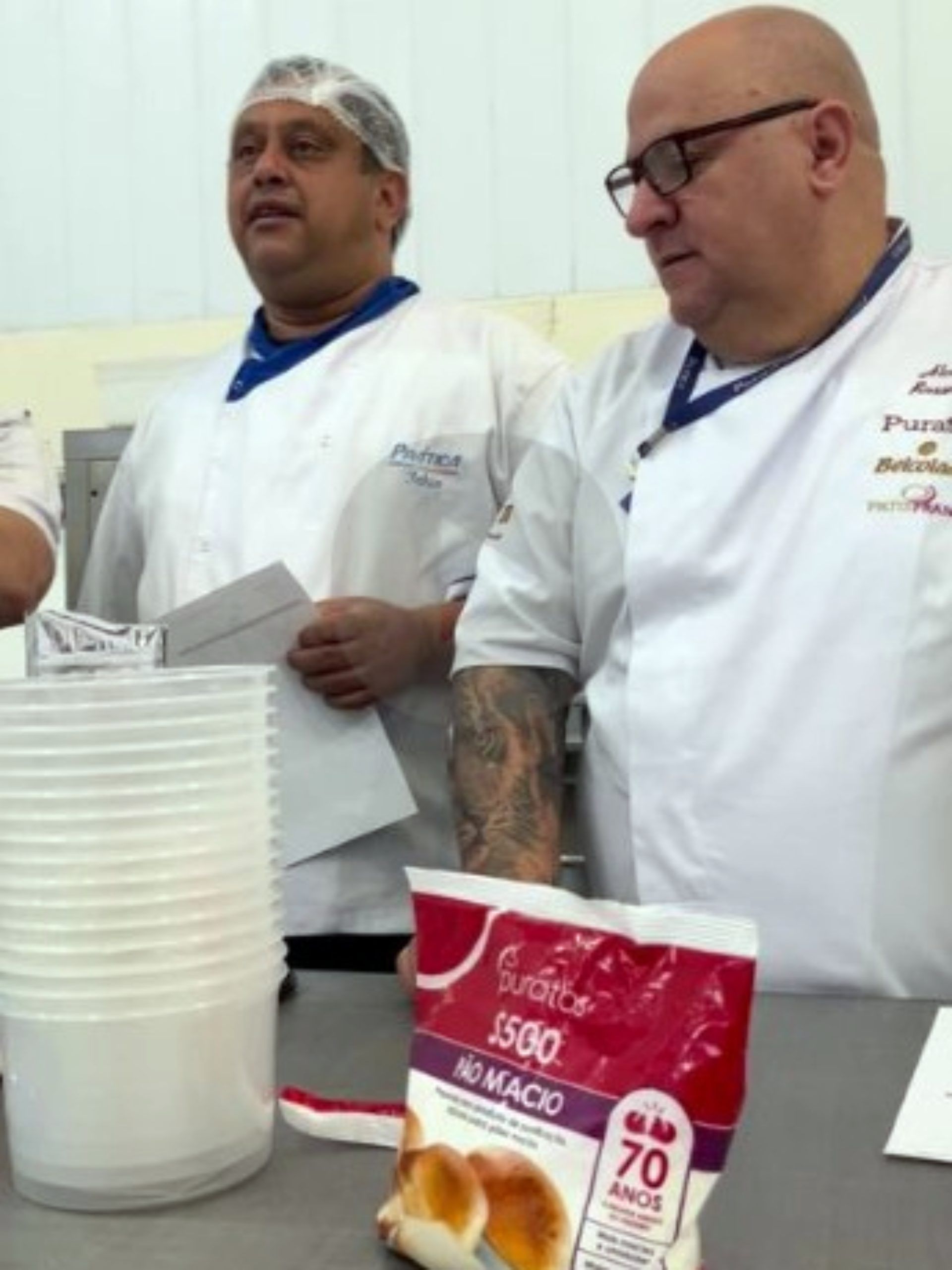 Dois homens em pé ao lado de uma sacola que diz 5550