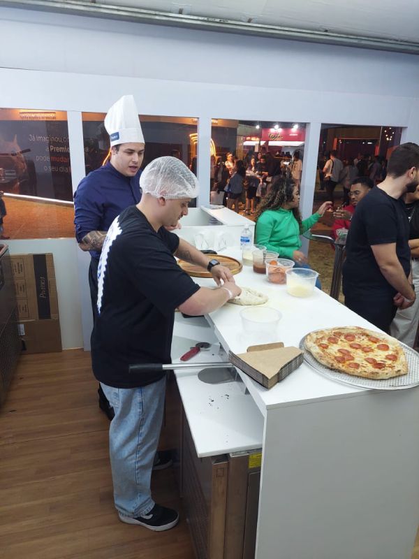 Um grupo de pessoas está preparando pizzas em uma cozinha