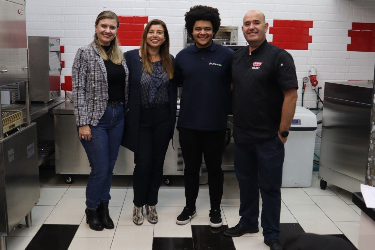 Um grupo de pessoas posa para uma foto em uma cozinha.