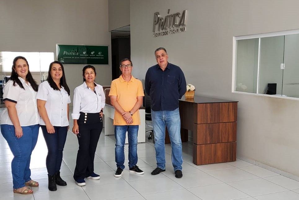 Um grupo de pessoas está de pé, uma ao lado da outra, em uma sala.