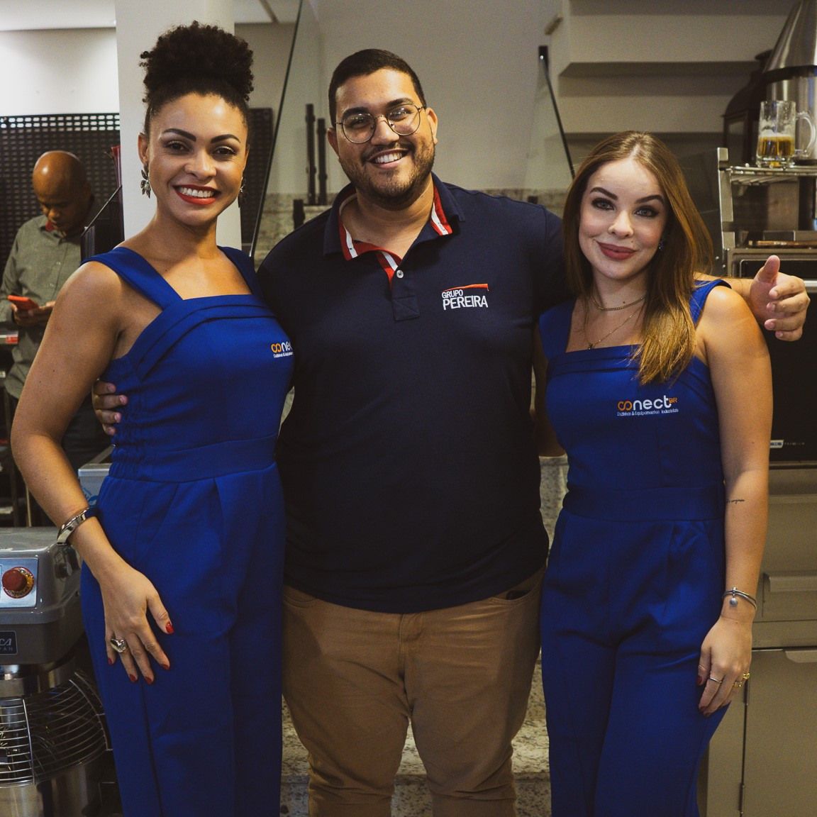 Um homem e duas mulheres estão posando para uma foto e o homem está vestindo uma camisa que diz notícias