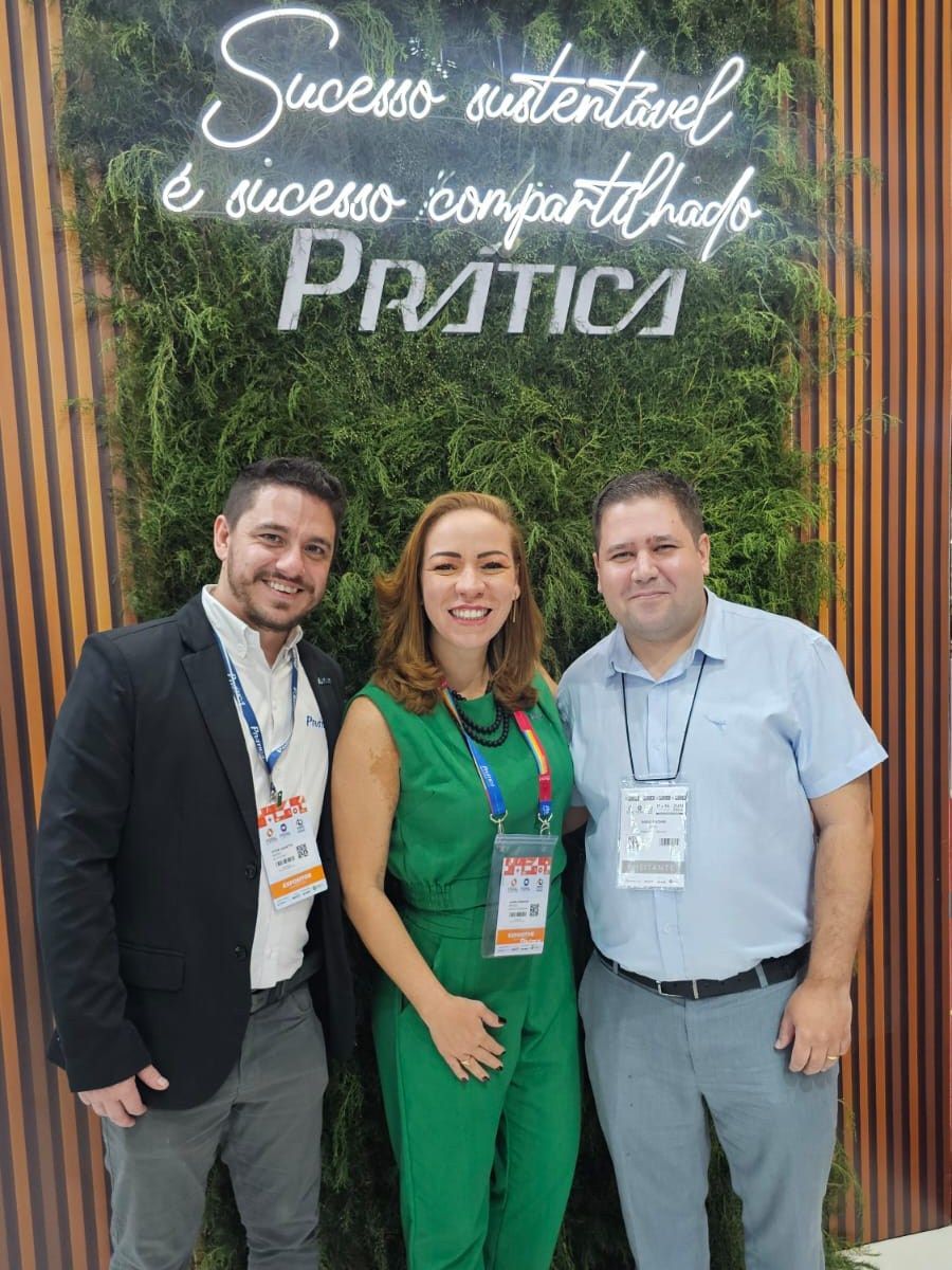 Três pessoas estão posando para uma foto em frente a uma placa que diz sucesso waterável