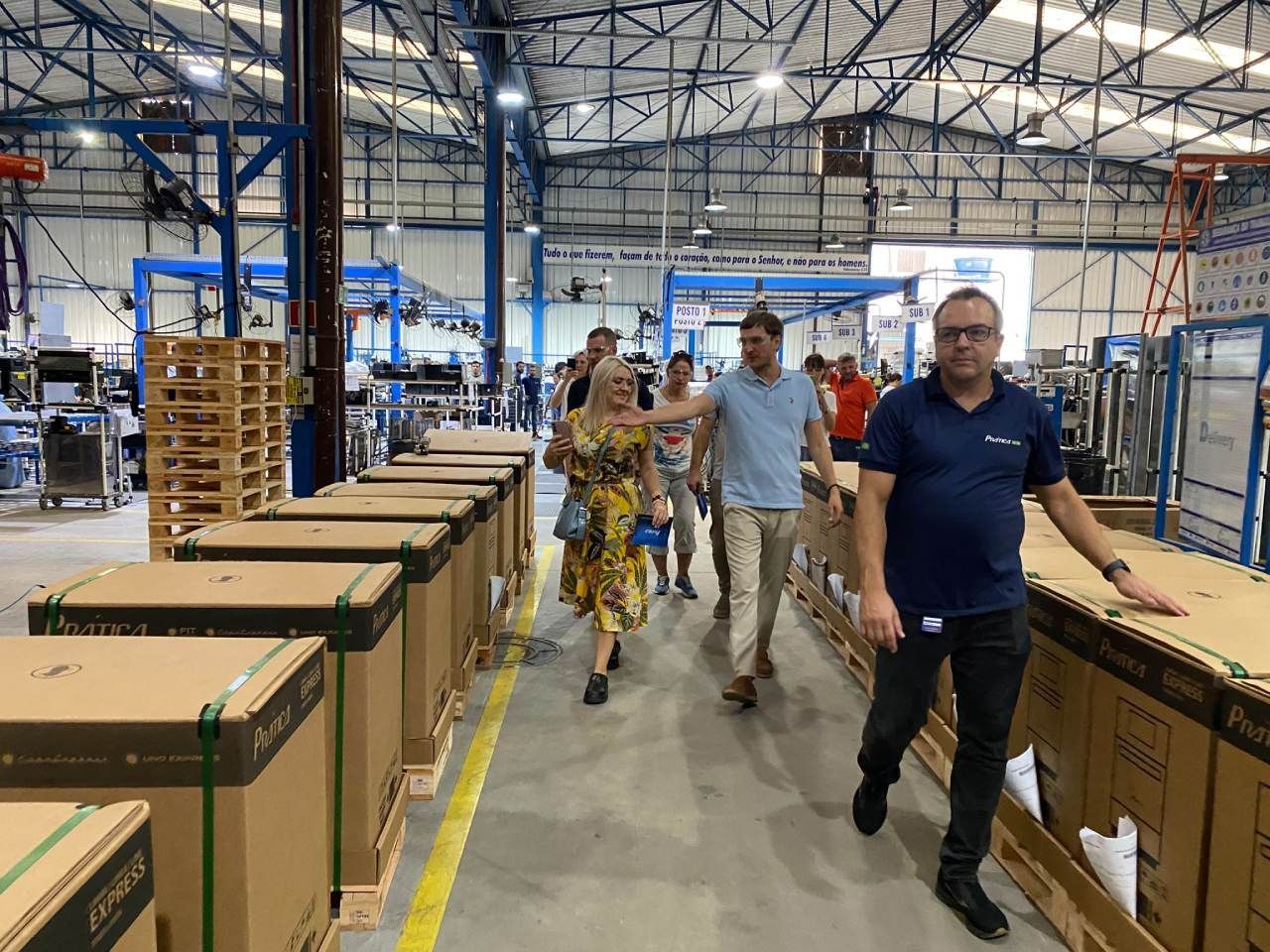 Um grupo de pessoas está caminhando por um armazém cheio de caixas.