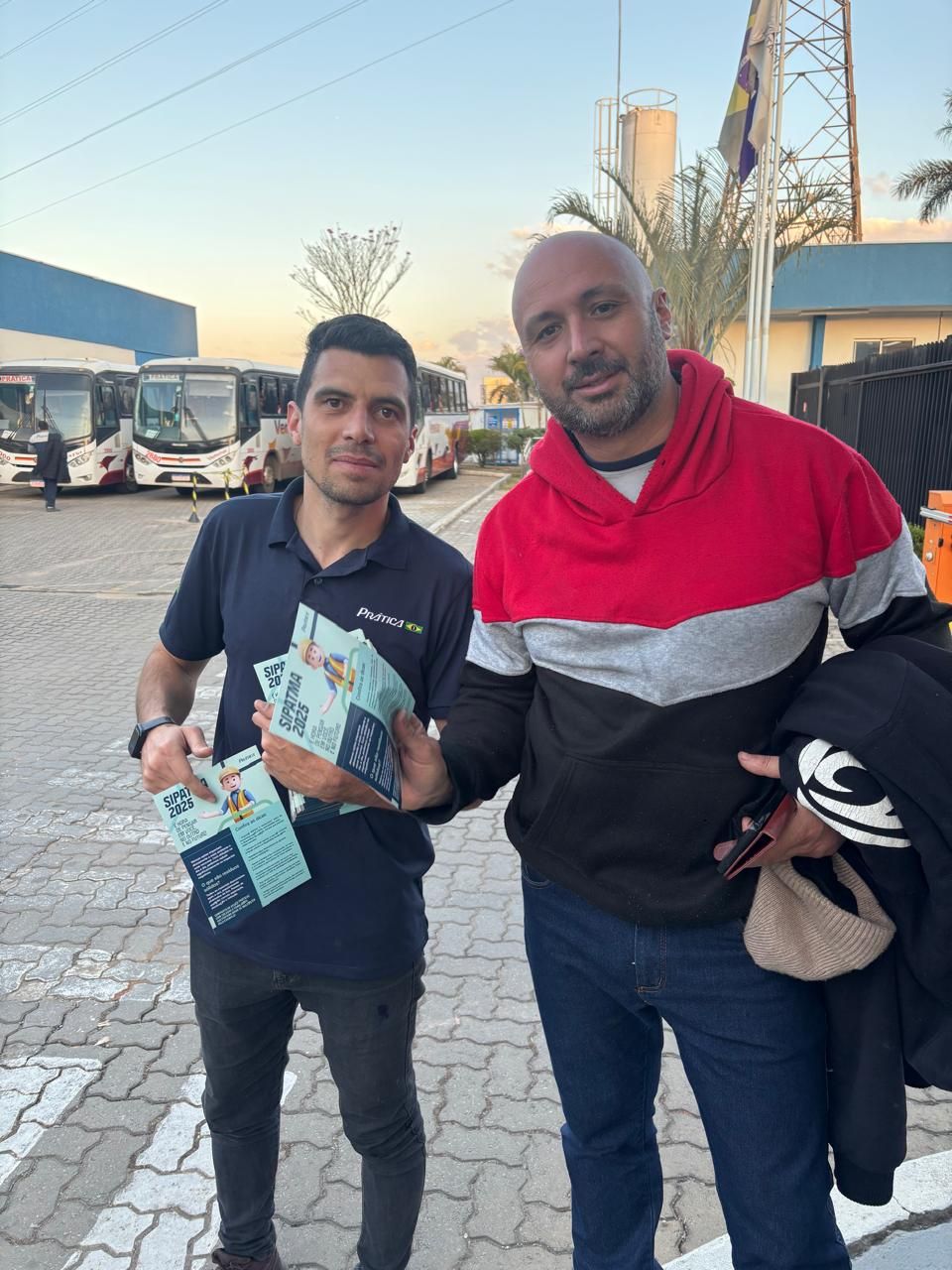Dois homens estão parados um ao lado do outro em um estacionamento.