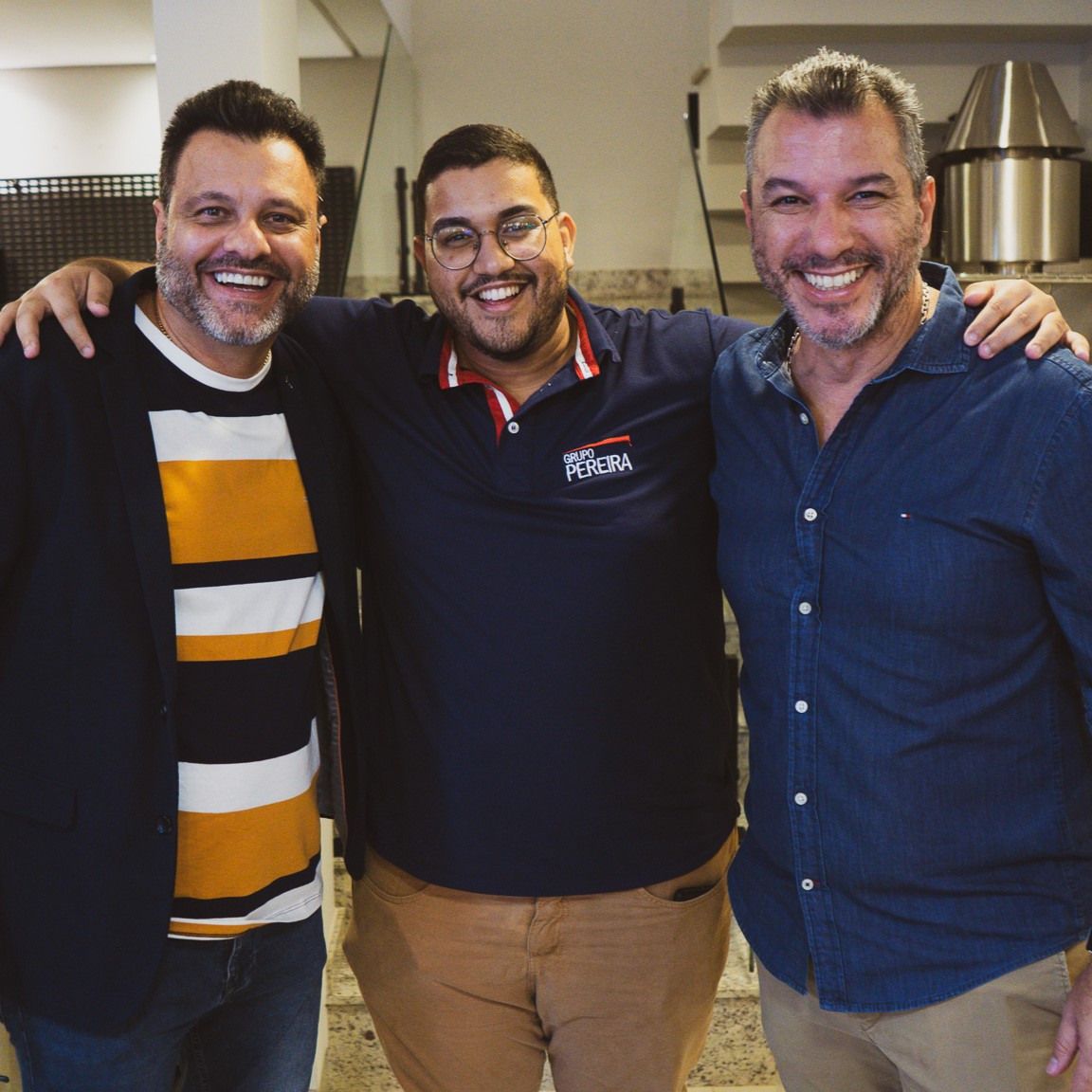 Três homens posando para uma foto, um deles vestindo uma camisa que diz silva