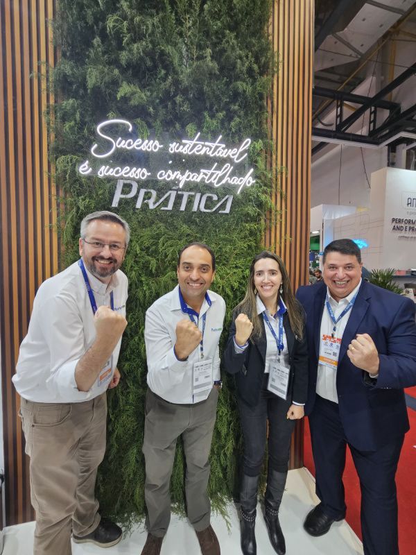 Um grupo de pessoas está posando para uma foto em frente a uma parede verde.