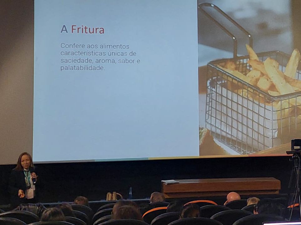 Uma mulher está fazendo uma apresentação sobre batatas fritas em frente a uma tela de projetor.