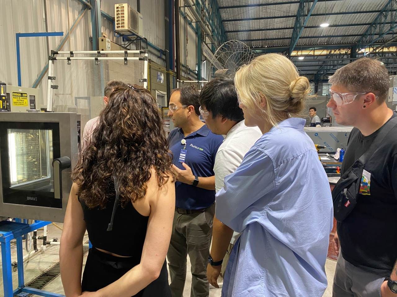 Um grupo de pessoas está em um armazém olhando para uma máquina.