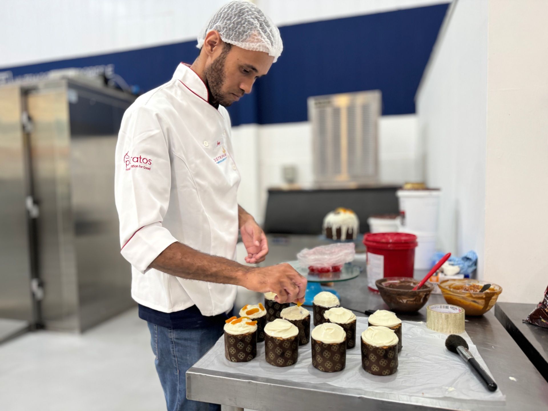 Chef decorando mini bolos em uma cozinha.