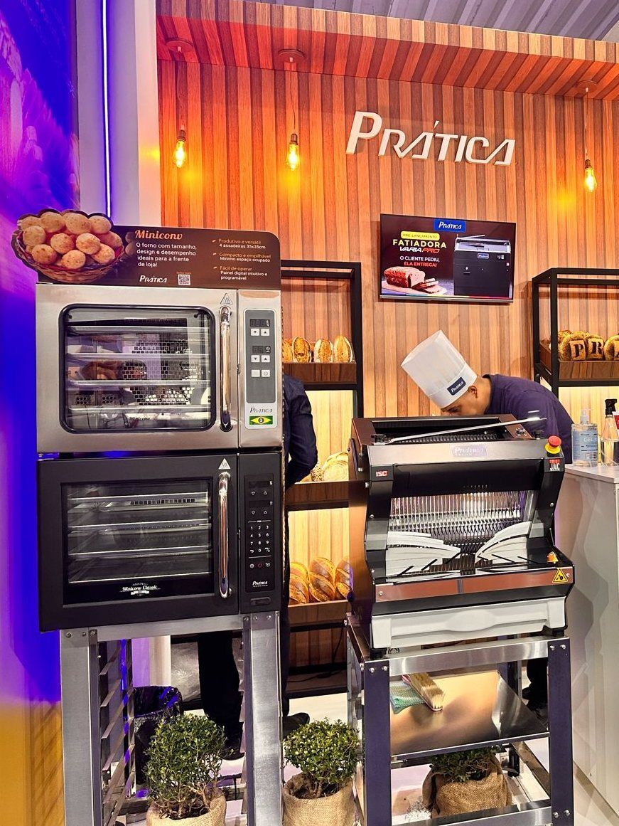 Um homem com chapéu de chef está trabalhando em uma máquina na cozinha.